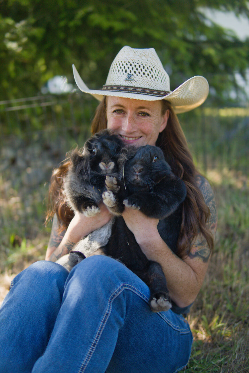 Founder smiling while holding two black rabbits